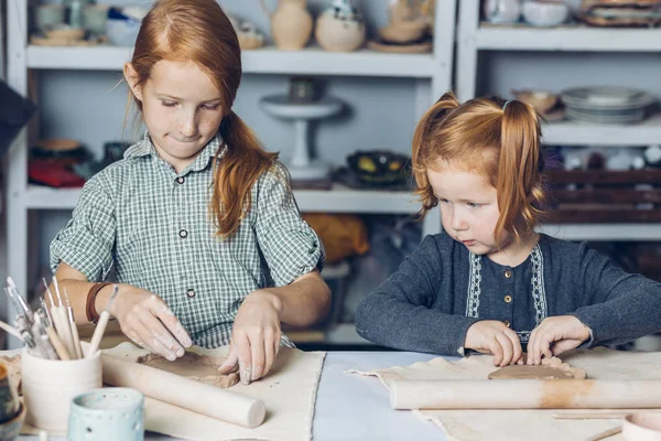 Hermana mayor de jengibre enseñando a su hermana pequeña a crear un plato de barro — Foto de Stock