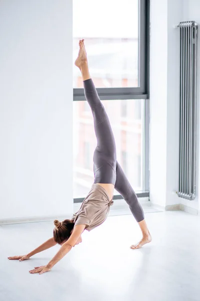 Спортивная стройная молодая женщина делает сложные аэробные упражнения йоги в помещении — стоковое фото