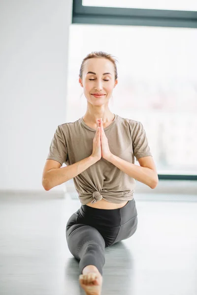 Full length portrait of young fit woman doing a yoga pose standing