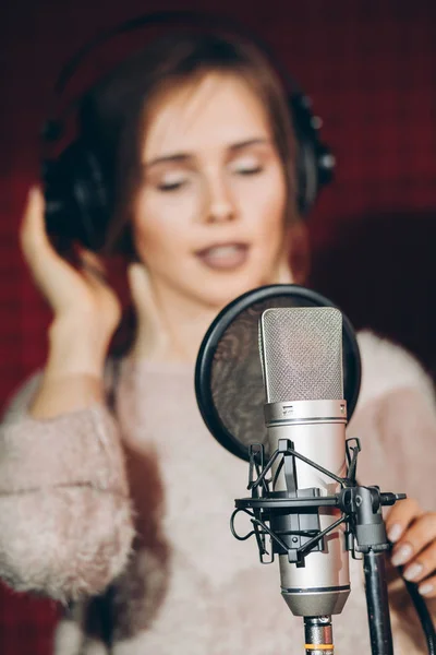 Cantando chica en auriculares en el fondo borroso —  Fotos de Stock