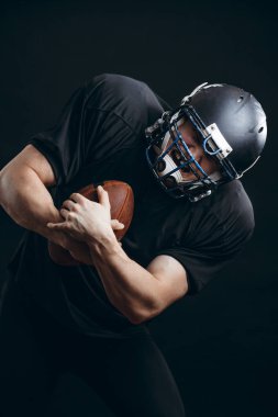 Amerikan futbolu sporcusu siyah stüdyo duvarından izole edildi.