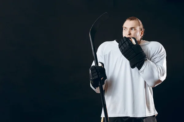 Guapo joven sosteniendo palo de hockey cubre la boca con la mano expresa miedo —  Fotos de Stock