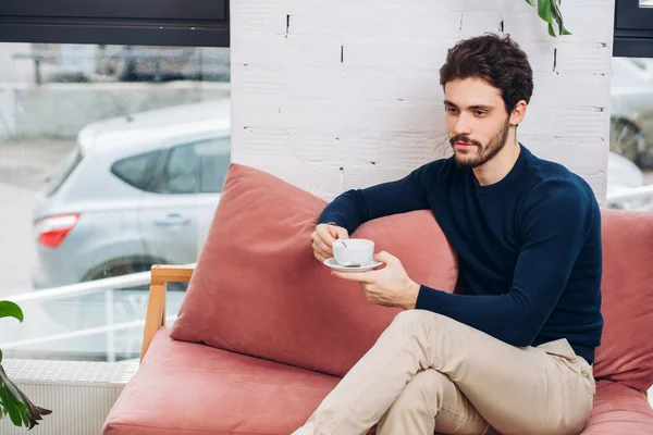 Schöner attraktiver Geschäftsmann hält eine Tasse in der Hand und denkt über seine Arbeit nach — Stockfoto
