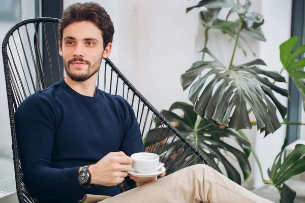 attractive male celebrity holding a cup of coffee and looking aside