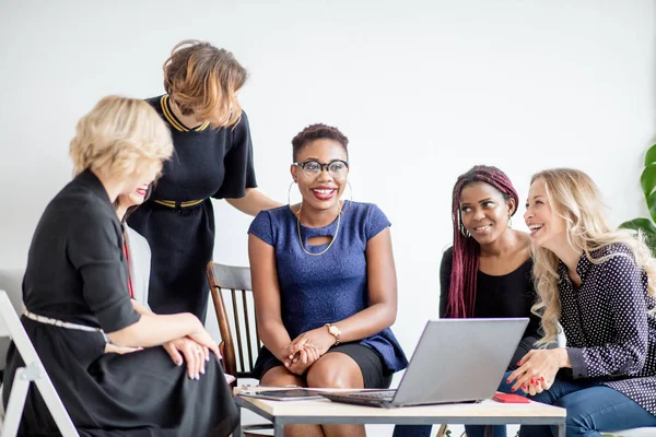 Mulheres positivas discutem plano de organização enquanto se sentam à mesa com laptop — Fotografia de Stock