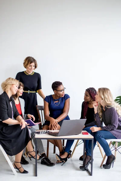 Mulheres positivas discutem plano de organização enquanto se sentam à mesa com laptop — Fotografia de Stock