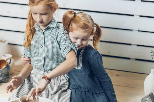 Pequeña niña abrazando a su hermana mayor mientras ella está haciendo un proyecto — Foto de Stock