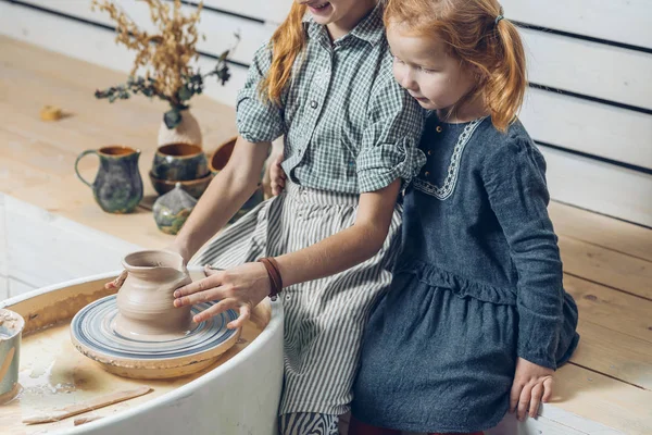 Niña viendo a sus hermanas trabajar con arcilla —  Fotos de Stock