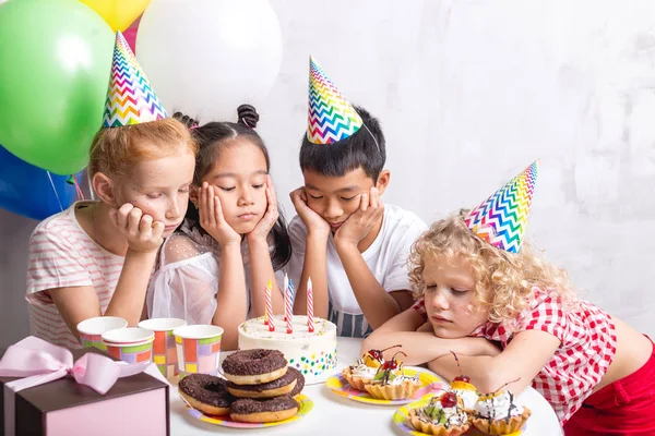 Bouleversé les enfants réunis autour de la table et regardant le gâteau savoureux — Photo