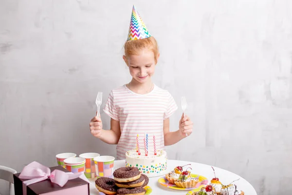 Menina incrível feliz segurando garfos e olhando para o bolo — Fotografia de Stock