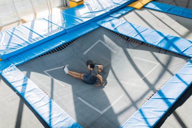 atlet trambolin üzerinde oturuyor