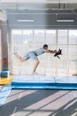 komik adam bir oyuncakla trambolinde zıplıyor