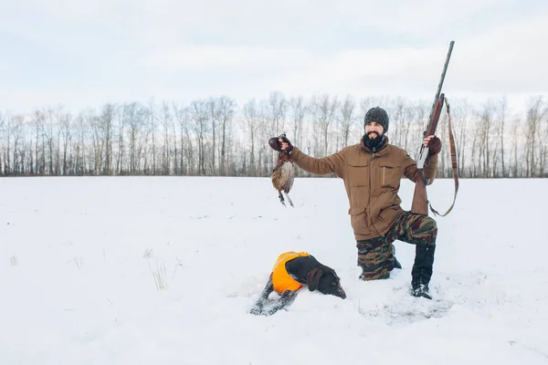 Positivo joven cazador agradable sosteniendo un pájaro muerto — Foto de Stock