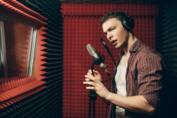 Knappe awesome zanger permanent met microfoon in de opname-kamer — Stockfoto