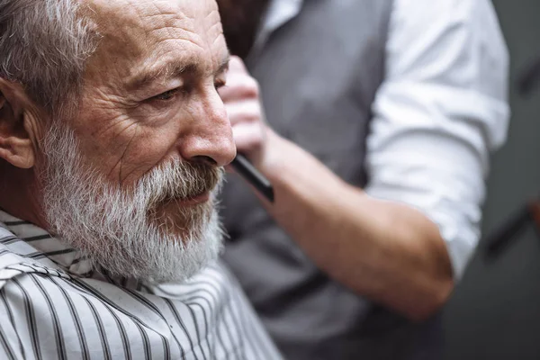 Primer plano de un peluquero s trabajo para un viejo guapo en la peluquería. —  Fotos de Stock