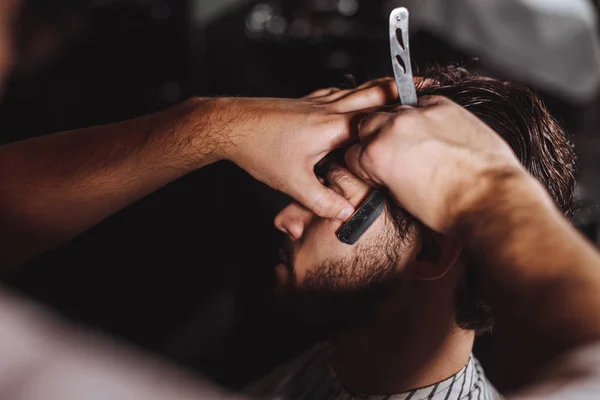 Un barbero hábil. Joven recibiendo un afeitado a la antigua con navaja de afeitar — Foto de Stock