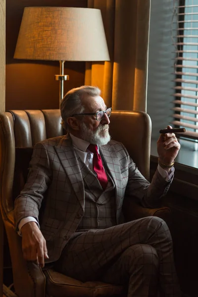 Klidný soustředěný dospělý muž architekt s šedovlasým vousem kouřící doutník — Stock fotografie