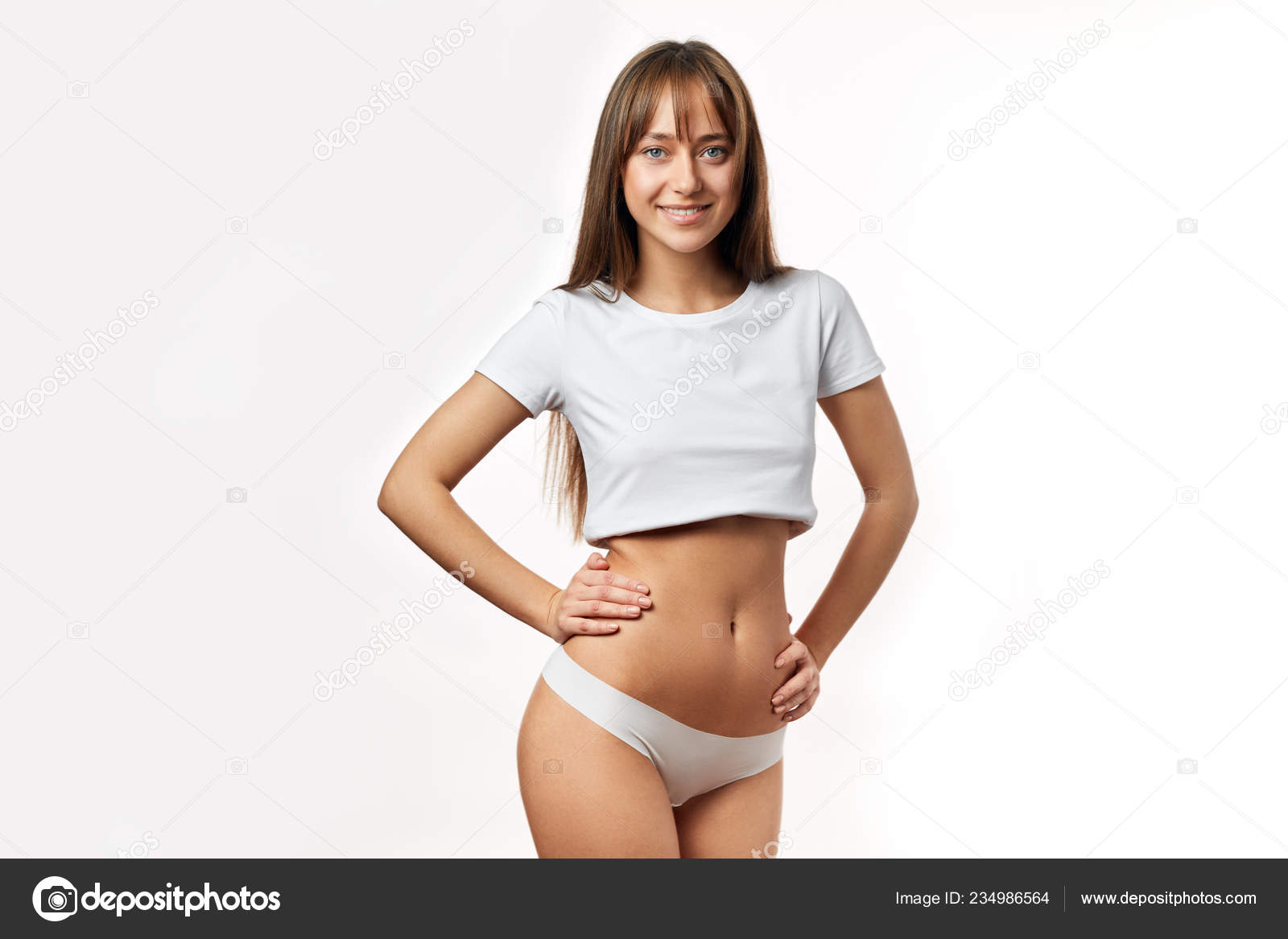 Attractive young woman in white underwear posing against white