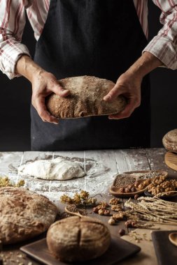 Tanınmayan baker taze pişmiş rustik organik somun ekmek elinde tutan