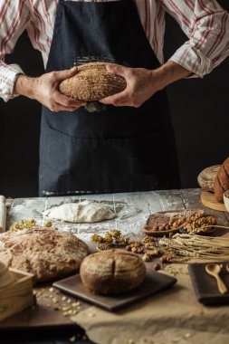 Tanınmayan baker taze pişmiş rustik organik somun ekmek elinde tutan