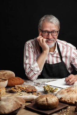 Yaşlı adam pişirme ürün yelpazesine gösteren. Ev yapımı hamur işleri, kırsal tarzı