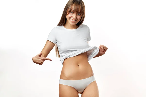 Schöne Frau in Unterwäsche testet Fettschicht auf der Taille. — Stockfoto
