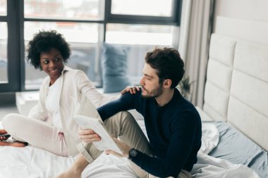 Irklar arası genç çift yatakta rahatlıyor ve eğleniyor. Afrikalı kadın