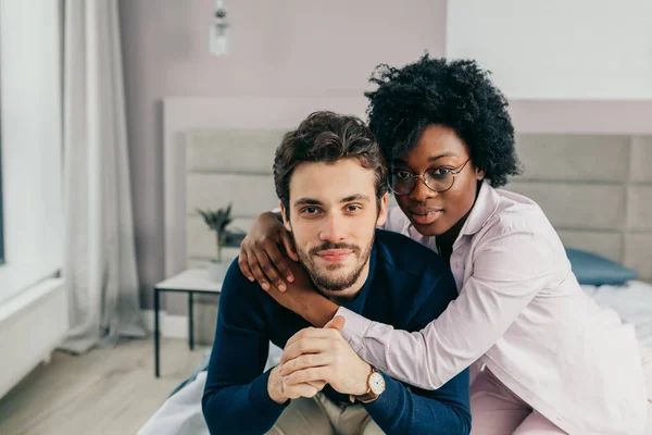 Interracial young couple relaxing and having fun on bed. African woman