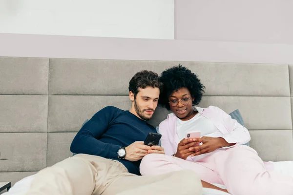 Amerikaanse man delen van foto 's met zijn mooie Afrikaanse vriendin in de slaapkamer — Stockfoto