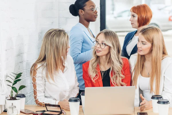 Grupo de mujeres jóvenes discutiendo proyecto durante el proceso de trabajo con el ordenador portátil. — Foto de Stock