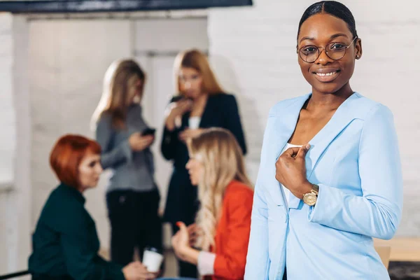 Mulher negra de negócios ajustando suas roupas em um fundo cinza — Fotografia de Stock