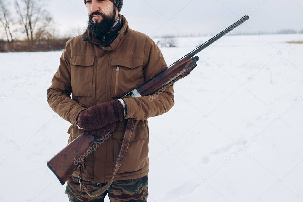 bearded hunter with rifle. Winter hunting.