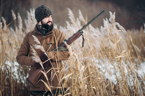 Feliz cazador alegre sosteniendo un rifle y mirando a un lado — Foto de Stock