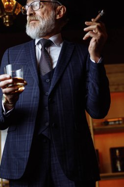 Geniş kenarlı şapkalı şık yaşlı adam ve zengin mavi adam elbisesi dumanı.