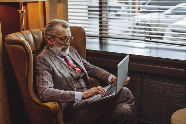 Fashionable elderly male writer wearing elegant clothes working