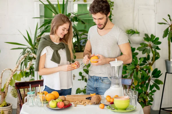 Underbara positiva man och kvinna peeling apelsiner i rummet — Stockfoto