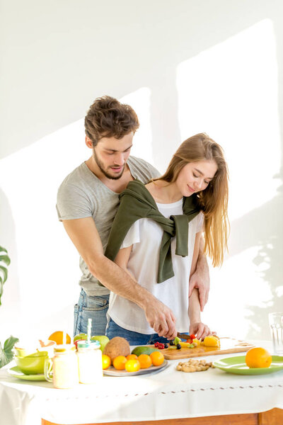 Happy sporty couple is preparing healthy food on light kitchen. Healthy food concept.