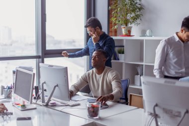Afro-Amerikan erkek meslektaşları Office tarafından çevrili bilgisayarda çalışma.