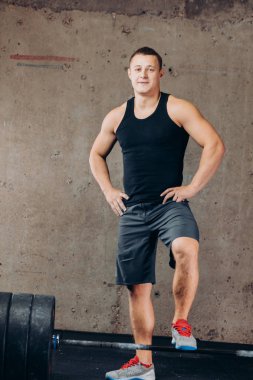 Halter duran ve kameraya bakarak çekici vücut geliştirmeci