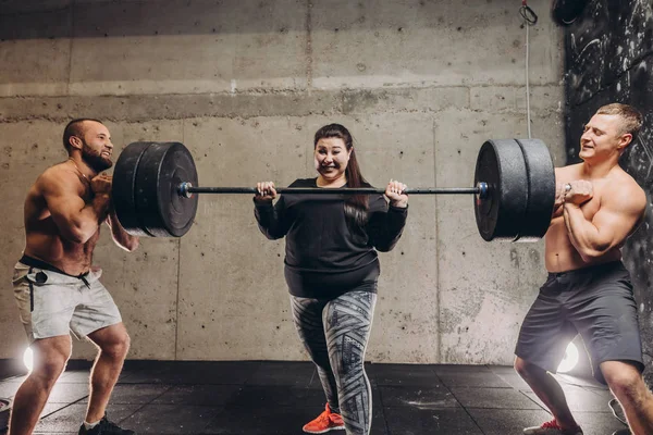Fat gek bezwete vrouw training met mannen in sportschool — Stockfoto