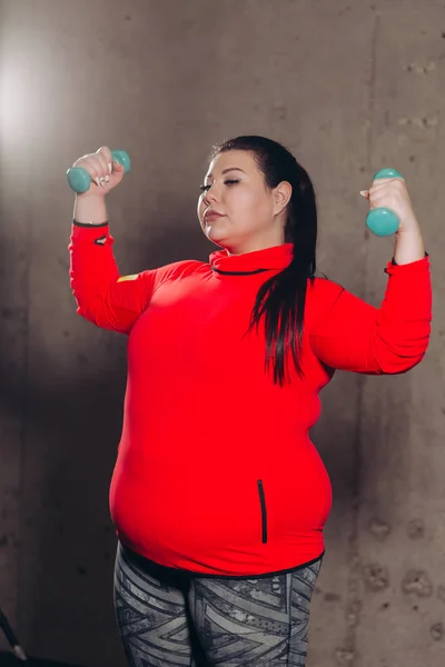 fat woman exercising with dumbbells in the studio