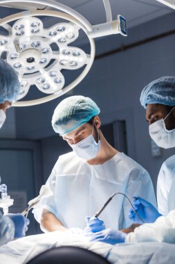 Genç doktor, ameliyathanede koruyucu maske takan bir cerrah.
