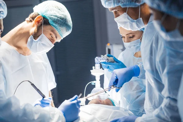 Diverse team van chirurgen, assistenten en verpleegkundigen die invasieve chirurgie — Stockfoto