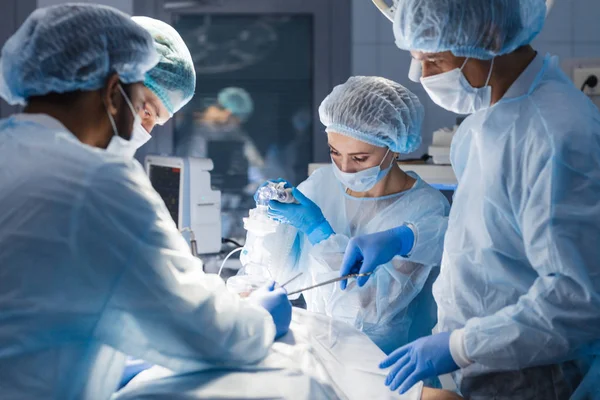 Zróżnicowany zespół chirurgów, asystentów i pielęgniarek wykonujących operacje inwazyjne — Zdjęcie stockowe