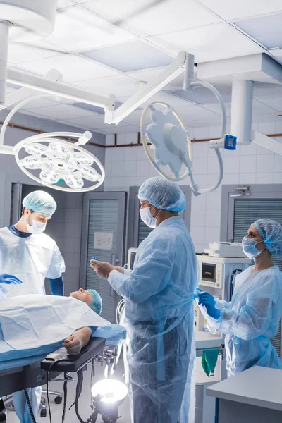 Surgery preparations. Surgical team preparing their patient for surgery — Stock Photo, Image