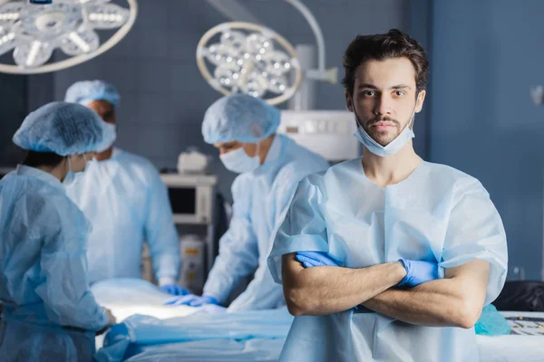 Surgeon looking at camera with colleagues — Stock Photo, Image