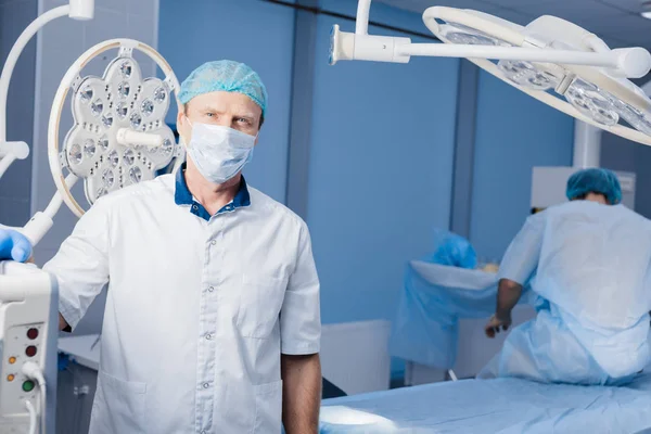 Médico senior, cirujano con máscara de protección médica en quirófano — Foto de Stock