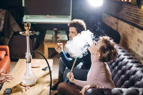 Hermosa mujer rubia fumando mientras se sienta con amigos — Foto de Stock