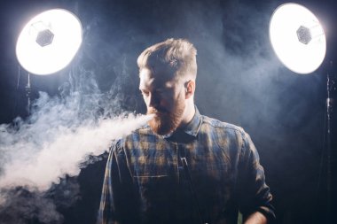 üzgün ciddi adam exhailing duman ve aşağı seyir