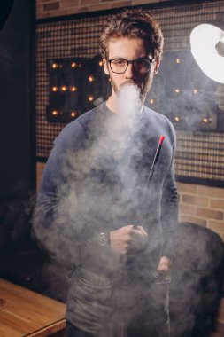 Dumanlı odada genç attrctive karanlık-haireed adam